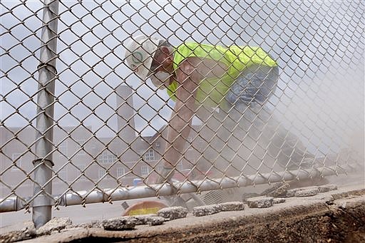 Joe Baecht, a laborer with Millstone Weber, uses a concrete saw on a lot which will eventually be turned into a soccer field at the Nahed Chapman school in St. Louis on Tuesday, July 5, 2016. (Cristina M. Fletes/St. Louis Post-Dispatch via AP)