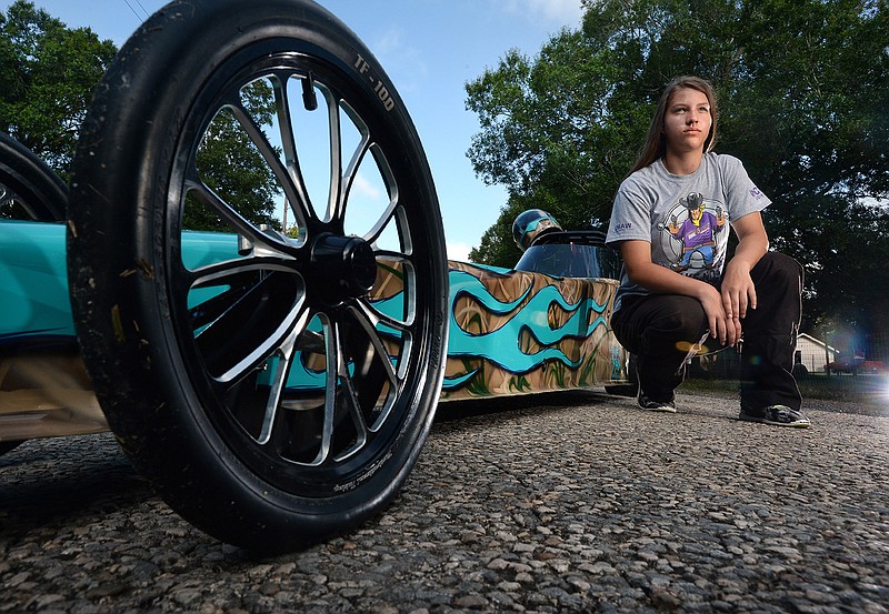 In a June 29, 2016 photo, Kinley Wolffordposes for a photo next to her dragster in Mauriceville, Texas. After only four months behind the wheel of her dragster, Wolfford, 12,  recently won the Western Conference of the National Hotrod Association's junior league.  