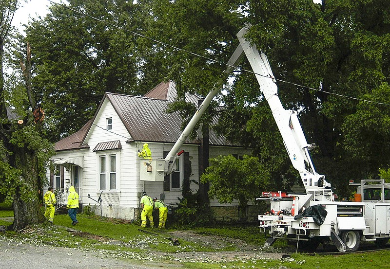 California City employees re-attach power lines to a house on Howard St. in California, after a tree limb tore the lines loose where they attached to the house. The crews were at work early on Thursday morning after the storm roared through.