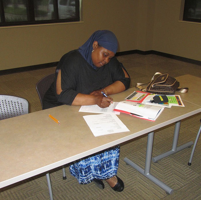 Pepita Shelvy fills out an application at the job fair Tuesday.