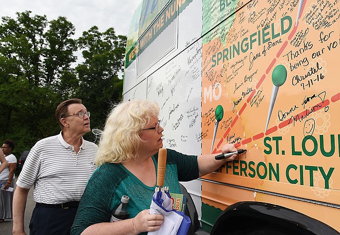 Wayne Lee waits his turn while Amy Rogers signs her name around Jefferson City on the map decorating a bus. Rogers is active in Faith Voices in Jefferson City, and Lee is a disability advocate; both were at Central Missouri Community Action to hear Sister Simone Campbell with Network's Nuns on the Bus.