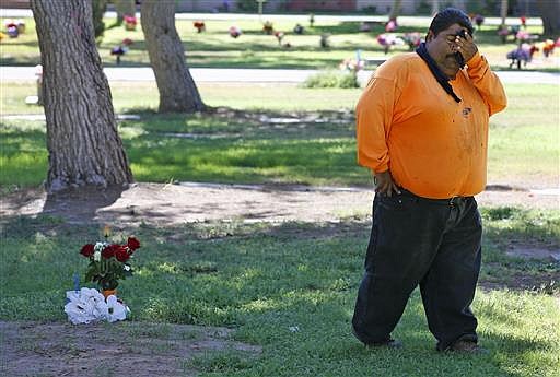 Margarito Castro, father of Manuel "Manny" Castro Garcia, 19, pauses for a moment as he visits his son's grave at a cemetery Thursday, July 14, 2016, in Phoenix. The teen was killed in June, and is one of a growing number of victims associated with a serial killer according to police.