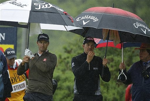 Adam Scott of Australia, left and playing partner Henrik Stenson of Sweden walk off the 12th tee under umbrellas as heavy rain falls during the second round of the British Open Golf Championships at the Royal Troon Golf Club in Troon, Scotland, Friday, July 15, 2016. 