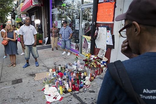 In this July 22, 2014 file photo, pedestrians stand beside a memorial for Eric Garner at the site where he died while being arrested by New York City police, in the Staten Island borough of New York. Two years after the police chokehold death of Garner made "I can't breathe" a rallying cry in the national protests about police killings of black men, federal prosecutors are still grappling with the question of whether to prosecute the white officer seen on videotape wrapping his arm around Garner's neck. 
