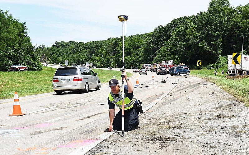 Sgt. Paul Kempke holds a tape measure in place as he and Sgt. Paul Meyers investigate the scene of a motor vehicle crash in which two people were killed Tuesday, July 12, 2016 on U.S. 54 in Holts Summit.