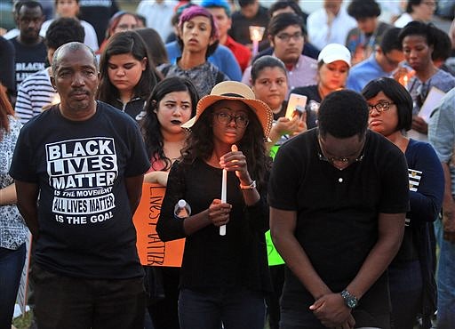 Supporters of the Black Lives Matter movement pray for those who lost their lives while confronting the police and for the police recently killed in Dallas, during a candlelight vigil at Archer Park in McAllen, Texas, Saturday, July 16, 2016. 