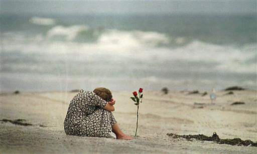  In this July 26, 1996, file photo, a woman sits near a rose she placed in the sand at Smith Point Park Beach in Shirley, N.Y. , as she mourns the loss of some of her friends who were on the flight crew for TWA Flight 800. 