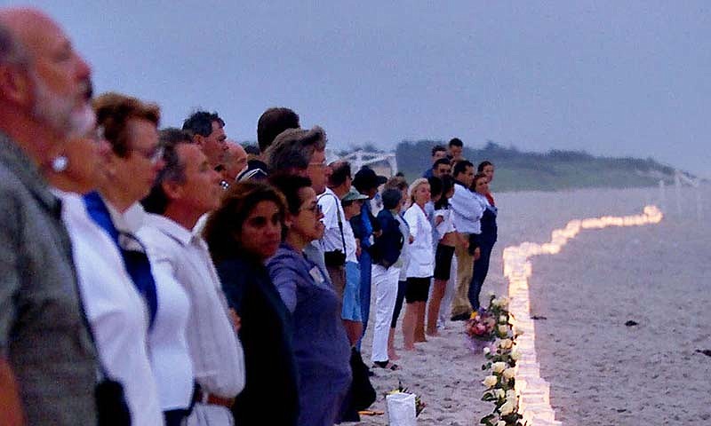 In this July 17, 2000, file photo, family members and friends of victims of TWA Flight 800 hold hands after lighting 230 candles on the beach at Smith Point County Park in Shirley, N.Y., near where the Boeing 747 crashed in the Atlantic Ocean off the waters of the park on July 17, 1996, killing all 230 people on board. Twenty years after the aircraft exploded in a fireball off Long Island, the passage of time has been a salve for some, but others will never get over the heartache. (AP Photo/Ed Betz, File)