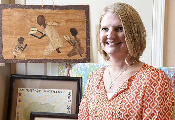 Crystal Burgen sits in front of HALO art therapy pieces made by students in the program. Burgen is the new director of HALO 