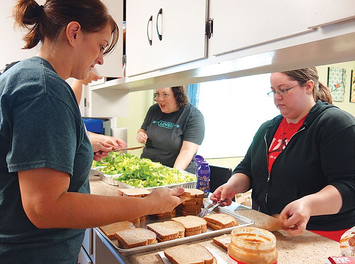 From left, Tara Snellen, Katie Mueller and Stephanie Romans prepare peanut butter and jelly sandwiches and salads for other volunteer workers from Freshwater Church.
