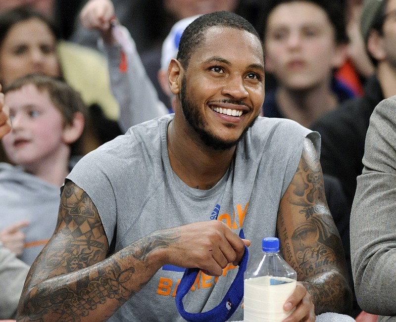 In this Jan. 24, 2014 file photo, New York Knicks' Carmelo Anthony smiles as he watches from the bench during the fourth quarter of an NBA basketball game against the Charlotte Bobcats,  at Madison Square Garden in New York. Signing day has arrived in the NBA, if the biggest free agents care to grab their pens. But its unclear if Anthony, Chris Bosh and Dwyane Wade _ who all might be waiting on LeBron James to go first _ are ready.