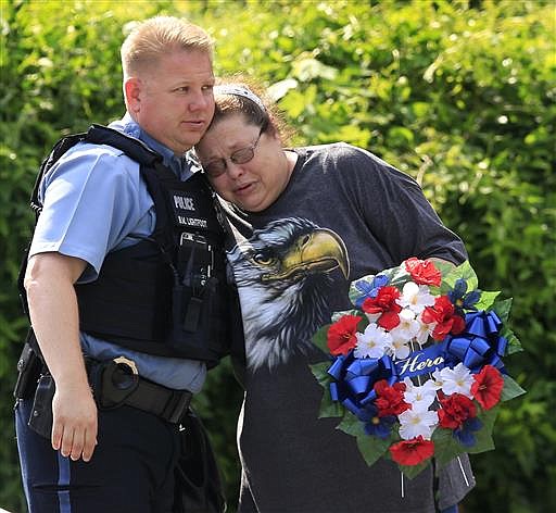 Kansas City, Kan., police officer Brad Lightfoot, left, consuls Susan Goble at the shooting scene of a police officer in Kansas City, Kan., Tuesday, July 19, 2016. Goble knows the family of the fallen officer and hoped to place a wreath near the site of the shooting.