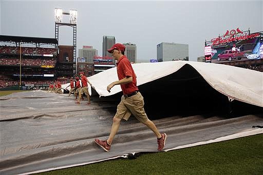 Members of the Busch Stadium grounds crew cover the field in anticipation of rain before the start of a baseball game between the St. Louis Cardinals and the San Diego Padres Tuesday, July 19, 2016, in St. Louis.