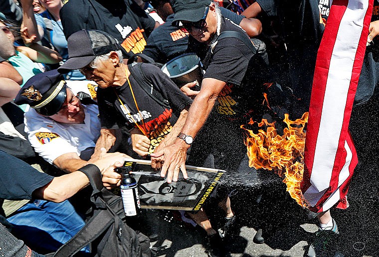 A law enforcement officer tries extinguish a burning American flag Wednesday in Cleveland during the third day of the Republican convention.  