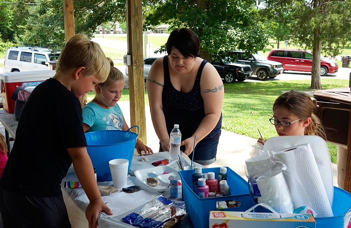 Jessie Staats and a group of children paint rocks with messages of happiness and peace to hide in plain sight.