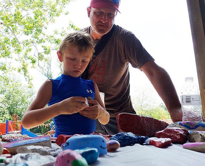 Anthony Nichols and his son, Eli, 8, look over a bunch of painted rocks that will be 'set free' soon as part the Fulton Rocks movement.    