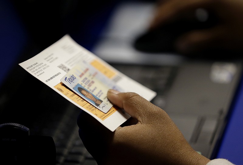  In this Feb. 26, 2014, file photo, an election official checks a voter's photo identification at an early voting polling site in Austin. A federal appeals court ruled Wednesday, July 20, 2016, that Texas' strict voter ID law discriminates against minorities and the poor and must quickly be scrubbed of those effects before the November 2016 election. Voters will still need to show identification at the polls under the decision by the New Orleans-based 5th U.S. Circuit Court of Appeals, according to attorneys who challenged the law, but a lower court will now also have to devise a way for Texas to accommodate those who cannot. 