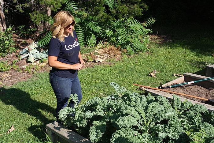 Brittney Eaton stands in front of kale growing in the community garden behind the Our House homeless shelter.