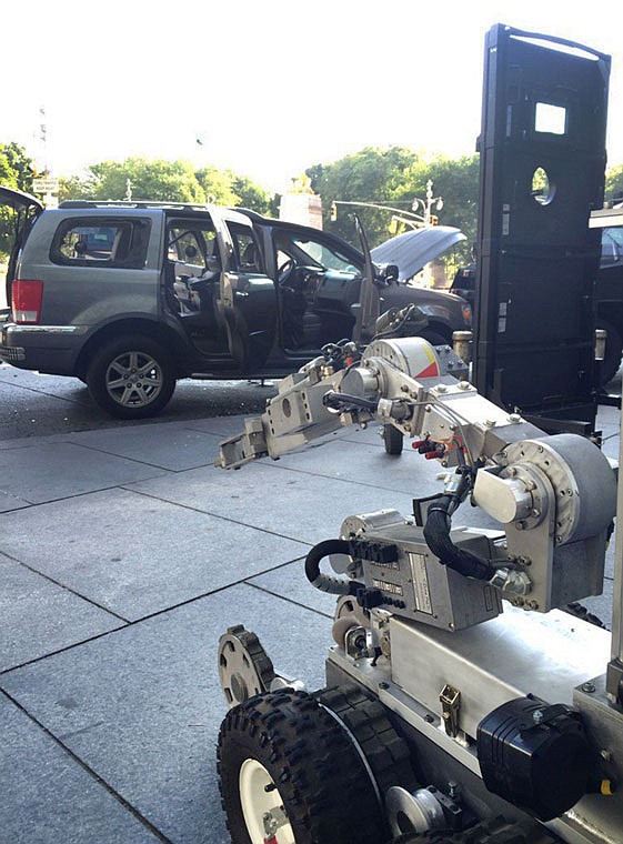 A police robot sits next to a suspect's vehicle following a standoff Thursday at Columbus Circle in New York. A man suspected of tossing a hoax bomb through the open window of a police vehicle was taken into custody after an overnight standoff, the New York Police Department said Thursday. 