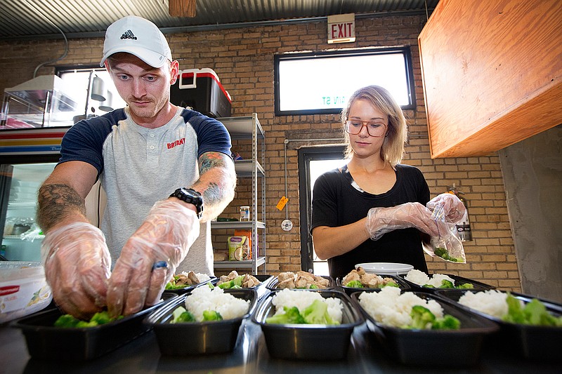 Bryant and Whitni Allen prepare to-go containers of chicken teriyaki Wednesday afternoon at their new takeout restaurant, Heat It Up, at 115 Main St. in downtown Texarkana, Texas. 