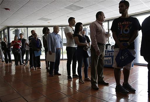 In this Tuesday, July 19, 2016, photo, people stand in line to register for a job fair, in Miami Lakes, Fla.
