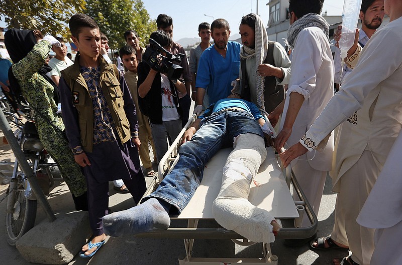 Afghans help an injured man at a hospital after an explosion struck a protest march, in Kabul, Afghanistan, Saturday, July 23, 2016. Witnesses in Kabul say that an explosion struck the protest march by members of Afghanistan's largely Shiite Hazara ethnic minority group, demanding that a major regional electric power line be routed through their impoverished home province. 