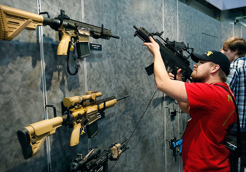 In this Jan. 19, 2016 file photo, Nolan Hammer looks at a gun at the Heckler & Koch booth at the Shooting, Hunting and Outdoor Trade Show in Las Vegas. Nearly two-thirds of Americans expressed support for stricter gun laws, according to an Associated Press-GfK poll released Saturday, July 23, 2016. A majority of poll respondents favor a nationwide ban on the sale of semi-automatic assault weapons such as the AR-15. 