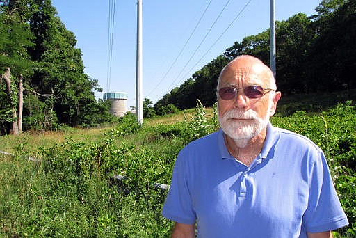 In this July 12, 2016 photo, Sid Bail, president of the Wading River Civic Association, poses outside the defunct Shoreham Nuclear Power Plant in Wading River, N.Y. Bail is among those who are opposing a proposal to build a solar energy project on the Shoreham property. The plan, which still needs regulatory approvals, would require cutting down 350 acres of trees. 