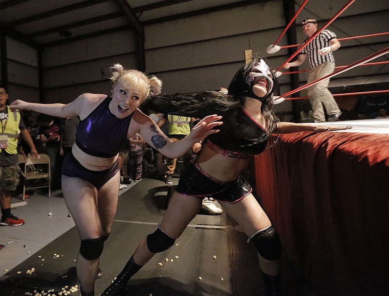 In this July 1, 2016 photo, Lucha Libre star Delilah drags her opponent Alley Cat back into the ring during a wrestling match in El Paso, Texas. The 5-foot-8 Delilah has wrestled professionally with New Era Wrestling for about 18 months, but her journey into the world of Lucha Libre began when she was 15 years old when she took an interest in the family business.