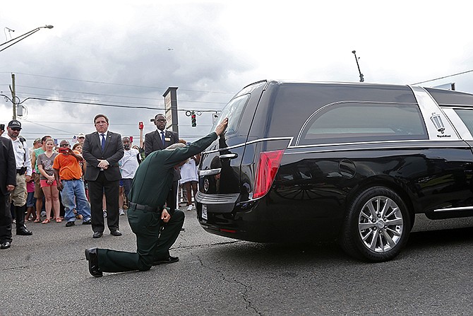 East Baton Rouge Sheriff Sid J. Gautreaux kneels and places his hand on the casket of deputy Brad Garafola after it was transferred from carriage to hearse Saturday, July 23, 2016, at the scene where Garafola and two police officers were killed in Baton Rouge, Louisiana.