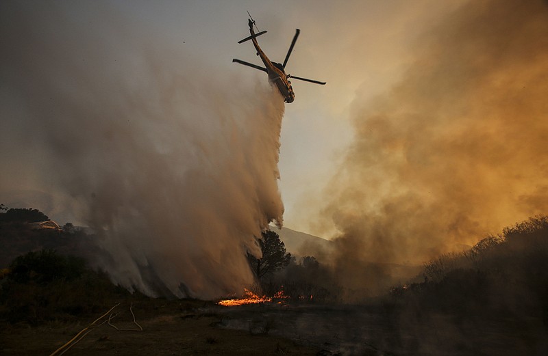 A helicopter makes a drop on a wildfire Sunday near Placenta Canyon Road in Santa Clarita, Calif. Thousands of homes remained evacuated Sunday as two massive wildfires raged in tinder-dry California hills and canyons.