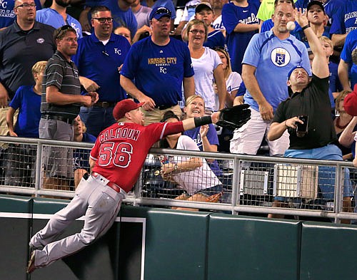 Angels right fielder Kole Calhoun leaps into the stands chasing a foul ball hit by Alcides Escobar of the Royals during the fifth inning of Monday night's game at Kauffman Stadium.