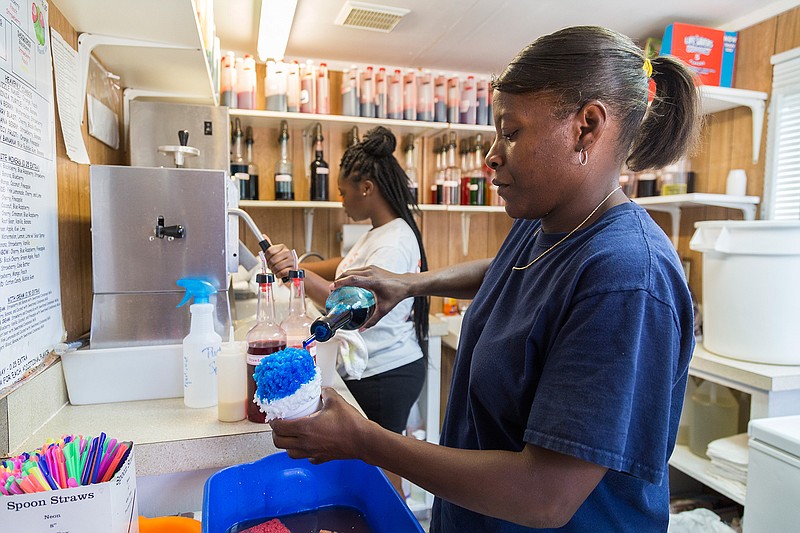 Brianna Black shaves ice Tuesday, July 26, 2016 as Annette Thomas pours blueberry flavoring on a snow cone at Heavenly Sno on Richmond Road. Heavenly Sno has been busy all summer, said Thomas, even on days that are cooler.