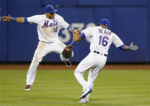 New York Mets center fielder Juan Lagares (12) and Mets left fielder Alejandro De Aza (16) celebrate after the second game of a baseball doubleheader against the St. Louis Cardinals, Tuesday, July 26, 2016, in New York. The Mets defeated the Cardinals 3-1.