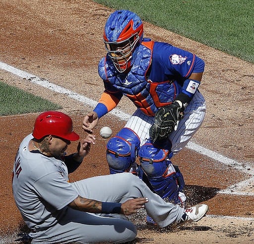 St. Louis Cardinals Yadier Molina, left, scores on a second-inning fielder's choice as the ball bounces off New York Mets catcher Rene Rivera, right, during the first game of a baseball doubleheader, Tuesday, July 26, 2016, in New York. St. Louis Cardinals starting pitcher Carlos Martinez hit into the play.