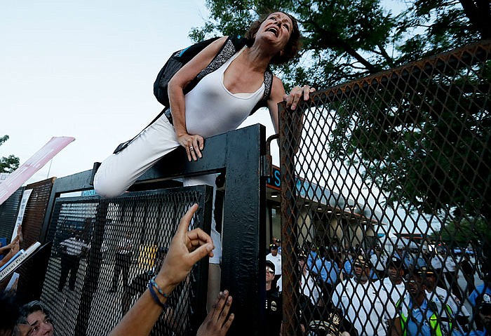 A protester climbs over the fence Tuesday near the AT&T Station in Philadelphia, near the Democratic National Convention.