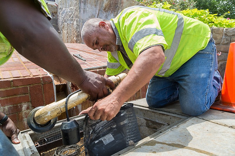 Otis Wimley and Johnny Barfield of Texarkana Water Utilities replace a pump and filter that were cleaned Wednesday, July 27, 2016 after a truck failed to turn right and crashed into the fountain early Tuesday morning behind the Downtown Post Office in Texarkana. The truck drained oil into the fountain, which had to be removed and the mechanical pieces of the fountain cleaned. 