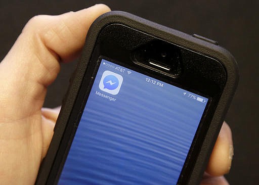 An Associated Press reporter holds a mobile phone showing the Facebook Messenger app icon in San Francisco, Wednesday, July 27, 2016. 