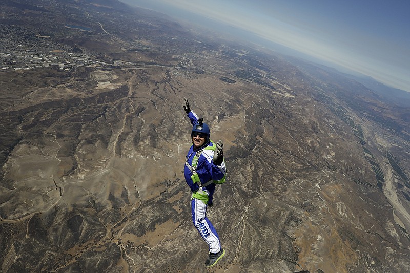 In this Monday, July 25, 2016, photo, skydiver Luke Aikins smiles as he jumps from a helicopter during his training in Simi Valley, Calif. After months of training, this elite skydiver says he's ready to leave his chute in the plane when he bails out 25,000 feet above Simi Valley on Saturday. That's right, no parachute, no wingsuit and no fellow skydiver with an extra one to hand him in mid-air.