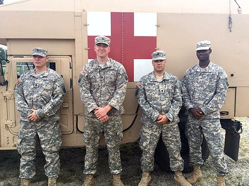 In this undated photo provided by the Massachusetts Army National Guard, four soldiers who rescued an elderly woman deep in a New Jersey woods pose next to a Humvee at Joint Base McGuire - Dix - Lakehurst in New Jersey. Two of the soldiers found the 87-year-old woman slumped over in the backseat of her car and unresponsive on Monday, July 25, 2016. They sought the help of two more soldiers, who were trained medics, then loaded the woman into a military ambulance. From left are Staff Sgt. Dana Francis and Sgt. Tommy Coppola; who found the woman and Spc. John Shively and Pfc. Aaron Amardey-Wellington, the medics who assisted in the rescue. (Staff Sgt. Steven Littlefield/Massachusetts Army National Guard via AP)