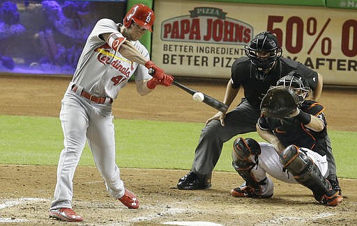 St. Louis Cardinals' Jeremy Hazelbaker hits a triple during the fifth inning of a baseball game against the Miami Marlins, Thursday, July 28, 2016, in Miami. At right is Miami Marlins catcher J.T. Realmuto. 
