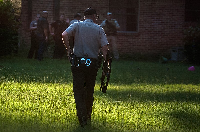 Bowie County sheriff's deputies investigate the area near the home of William Thomas Fugate, 26. Deputies searched for Fugate after a man who lived in the area called to report him walking down the road with a shotgun, according to reports. Fugate allegedly evaded deputies on foot and returned home before leaving again without the weapon when he heard police sirens, Sheriff James Prince said.