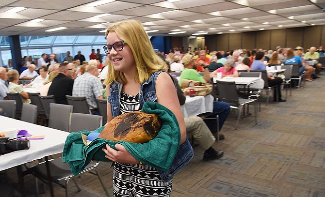 Molly Suthoff, of St. Thomas 4-H Club, carries her cured ham back and forth in front of the crowd in an effort to garner a high bid. She donated half of the proceeds to Dr. Tamara Hopkins' office in support of her grandmother who's undergoing treatment for cancer.