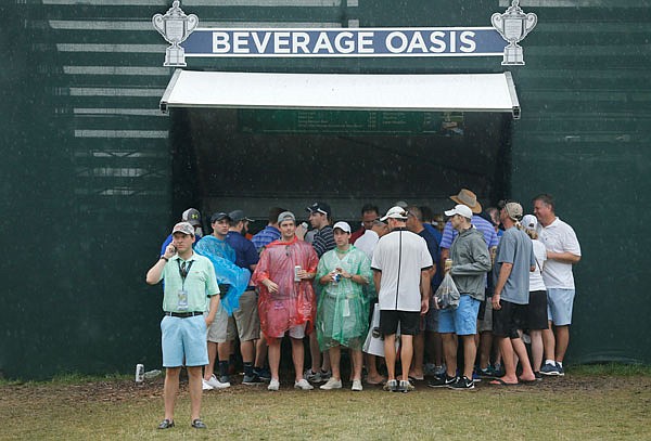 Fans take cover near the 18th green during a weather delay in Saturday;s third round of the PGA Championship at Baltusrol Golf Club in Springfield, N.J.