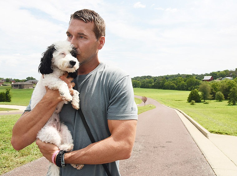 Brandon McMillan takes a break between takes as camera operators shoot video segments to be used in an upcoming episode of "Lucky Dog." The show airs at 9 a.m. Central Time on Saturdays on CBS and will feature Olive, shown here, a rescue dog he's trained to be a therapy dog for children in the local Court-Appointed Special Advocates program.