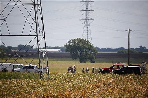 Investigators surround the scene in a field near Lockhart, Texas where a hot air balloon carrying at least 16 people collided with power lines Saturday, July 30, 2016, causing what authorities described as a "significant loss of life." (Ralph Barrera/Austin American-Statesman via AP)