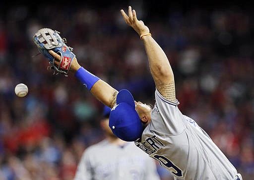 Kansas City Royals third baseman Cheslor Cuthbert (19) is unable to catch a pop fly hit by Texas Rangers' Mitch Moreland during the fifth inning of a baseball game, Saturday, July 30, 2016, in Arlington, Texas. Umpire Chris Conroy initially ruled that the ball was foul but after Rangers manager Jeff Banister argued against the call the umpiring crew consulted and the hit was ruled fair. 