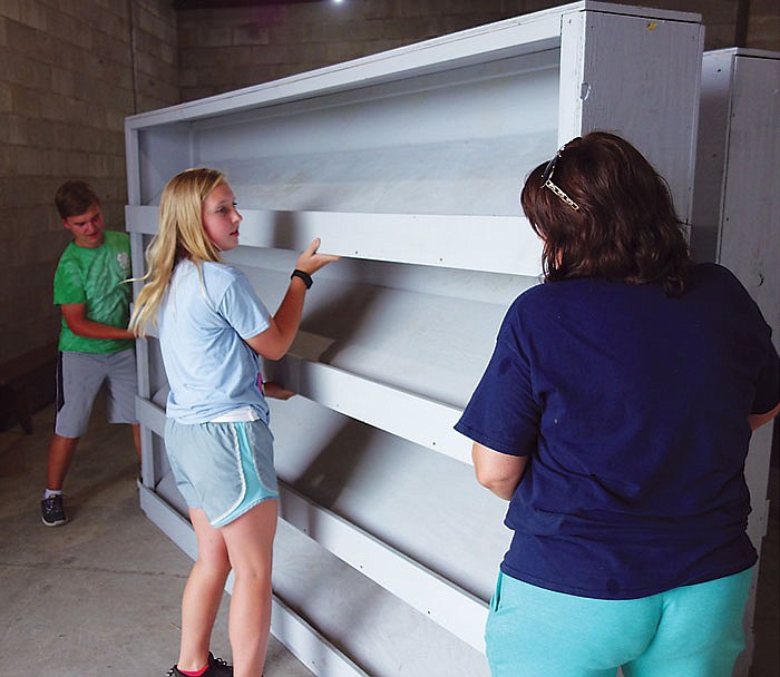 From left, Troy Ludwig, Elisabeth Dunn and Sara Koenigsfeld help move shelves into storage Sunday after the Jefferson City Jaycees Cole County Fair wrapped up Saturday. Members of the Jefferson City 4-H Club helped with cleanup at the 4-H building on the fairgrounds.