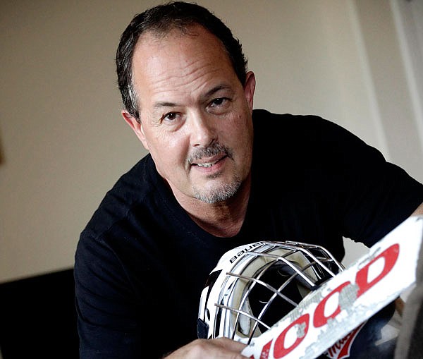 Tim Richmeier poses for a photo with some of his 15-year-old son's hockey equipment, in Phoenix. Richmeier was spending about $5,000 a season using his tax refunds, halting contributions to his 401(k) and putting travel expenses on a credit card, including $6,000 he's still paying off, so his son could play on a travel hockey team.