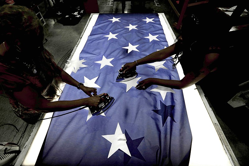 Employees Lottie Penick, left, and Melissa Hodnett iron stars onto a United States flag Wednesday, July 6, 2016, at Annin Flagmakers in South Boston, Va. 